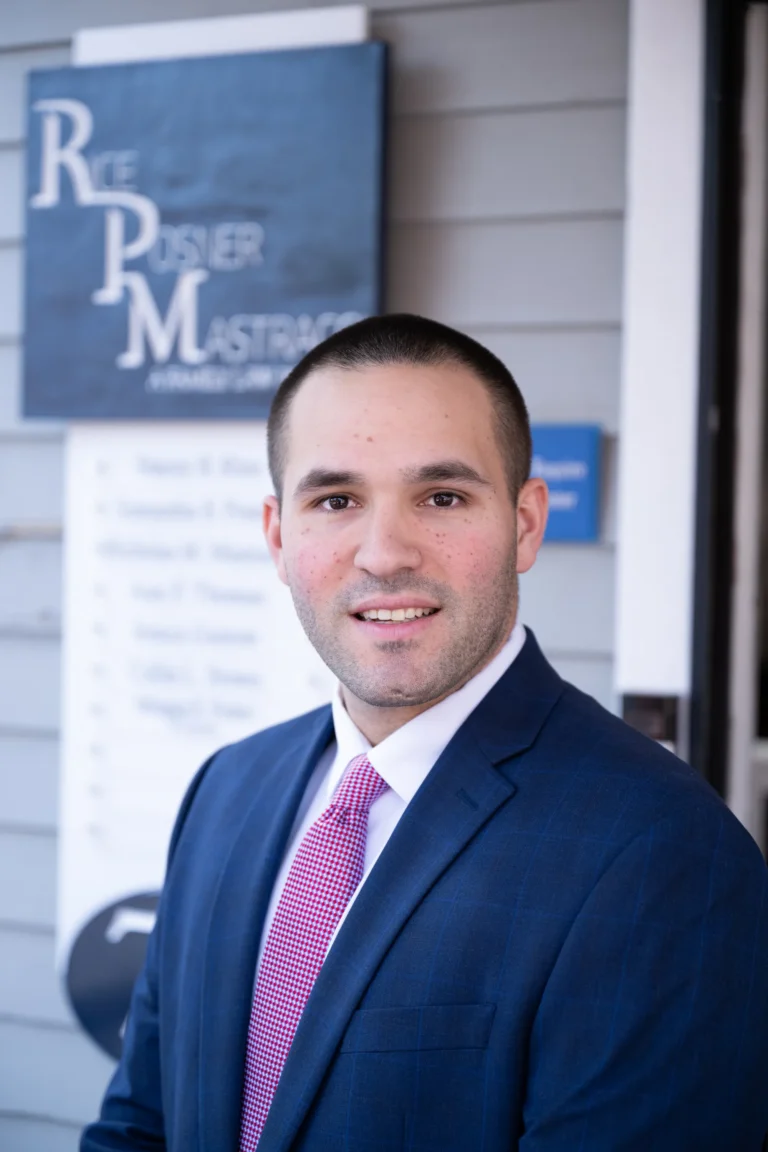 Professional man in blue suit and red tie standing in front of a law office sign.