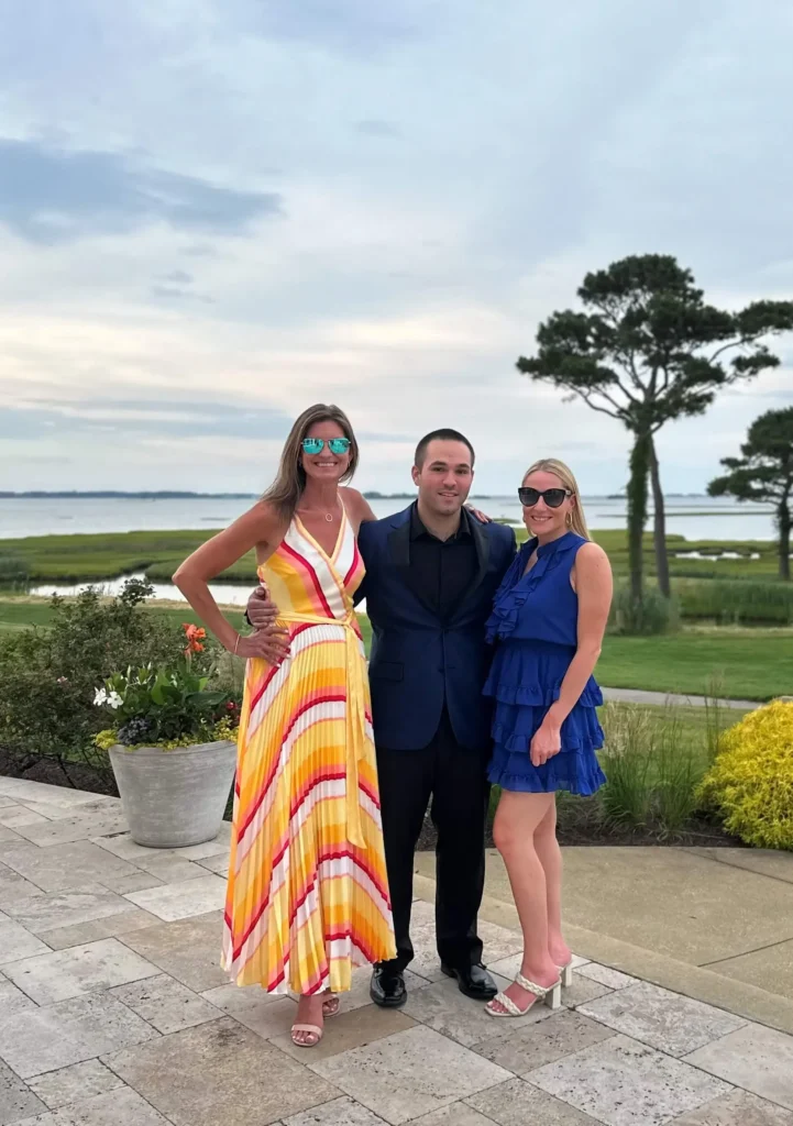 Three individuals in formal attire pose together for a photograph, smiling and standing closely.