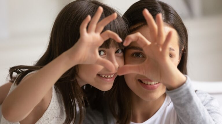 happy mother and daughter showing heart sign with fingers
