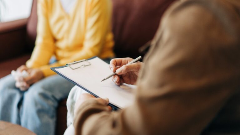 psychologist's hands writing down notes about a patient in a notebook