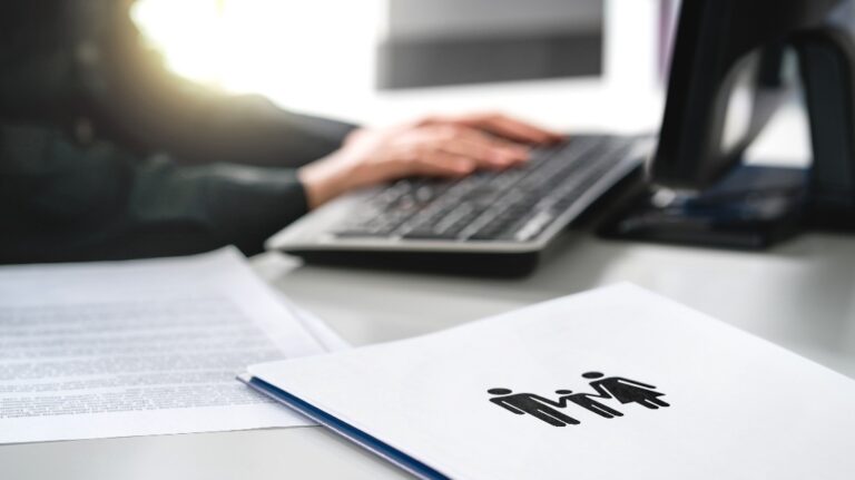 A lawyer works on a computer next to documents