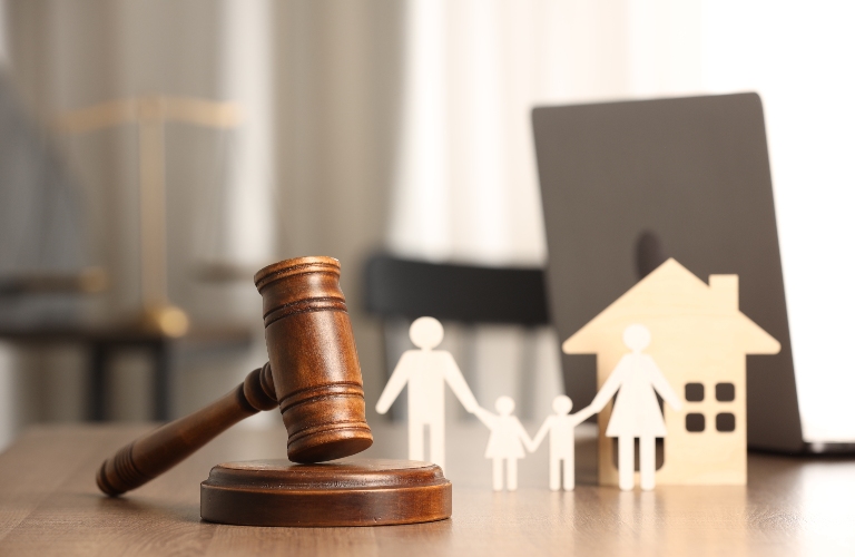 Gavel, figures of parents with children and house on wooden table