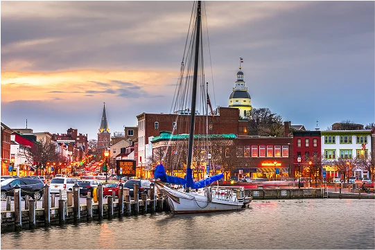 A sailboat is securely docked in calm waters, with reflections shimmering on the surface