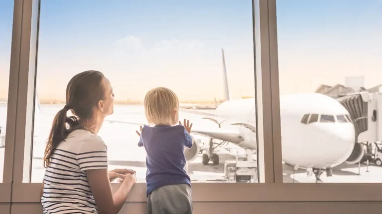 Woman and child looking through airport window at a parked white airplane outside.