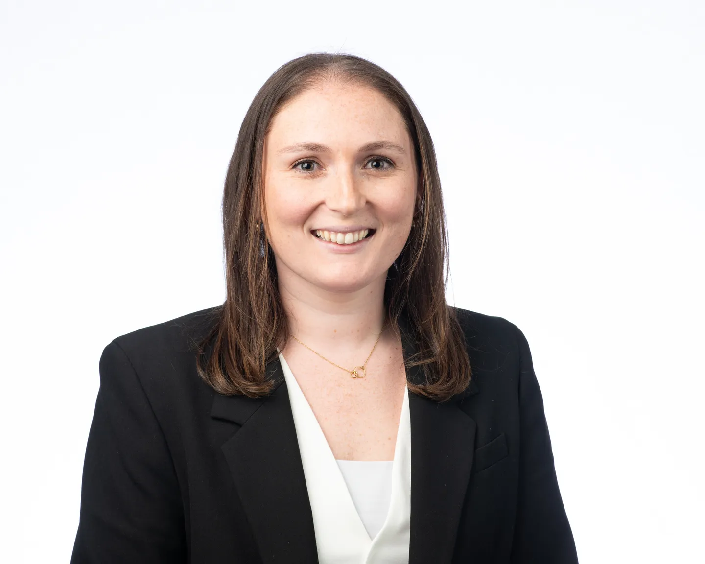 Professional headshot of a smiling woman with brown hair wearing a black blazer and white blouse.